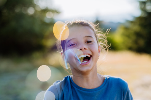 A portrait of a beautiful little girl laughing when having fun in summer in nature.