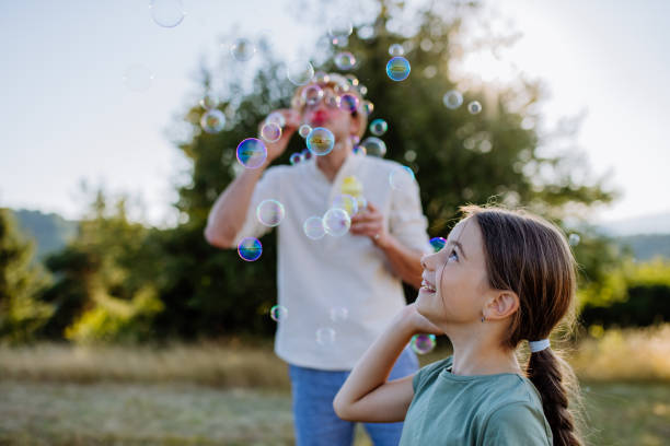 istock Young father and his little daughter having fun while blowing soap bubbles on a summer day in nature. 1419045742