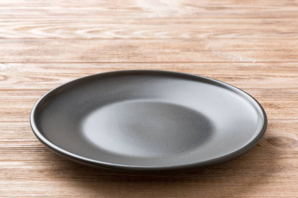 istock Perspective view of empty black plate on wooden background. Empty space for your design 1419047217