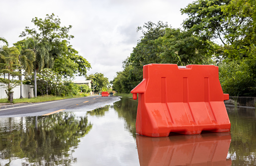A low angle view of orange plastic barricades placed on a flooded road.