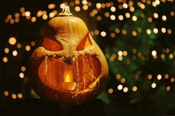 Scary smile Jack O Lantern pumpkin sitting in the table with garlands lights on background. Decoration for Halloween in club, market or cafe.