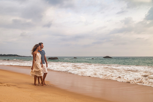 Happy couple together hugging having on tropical sandy beach at sea background. Beauty couple enjoying honeymoon summer at ocean coastline. Lovely man and woman relaxing happiness. Copy text space