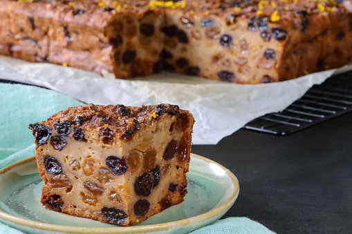 Stock photo showing close-up view of plates containing bread pudding sliced squares. This dessert is made with stale bread, mixed dried fruit, mixed peel, mixed spice, milk, eggs, light muscovado and demerara sugar, lemon zest and butter.