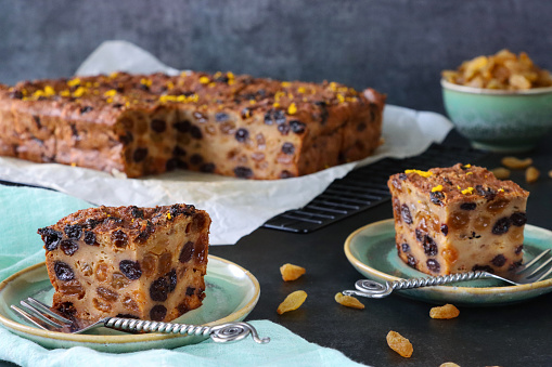Stock photo showing close-up view of plates containing bread pudding sliced squares. This dessert is made with stale bread, mixed dried fruit, mixed peel, mixed spice, milk, eggs, light muscovado and demerara sugar, lemon zest and butter.