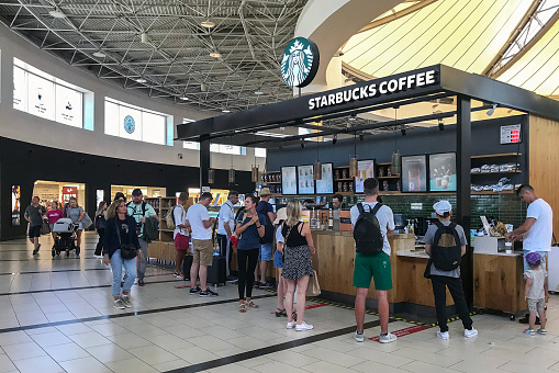 Passengers waiting for their flight queing up on a Starbucks coffee and snack bar for a drink or a piece of cake at  Antalya Airport.