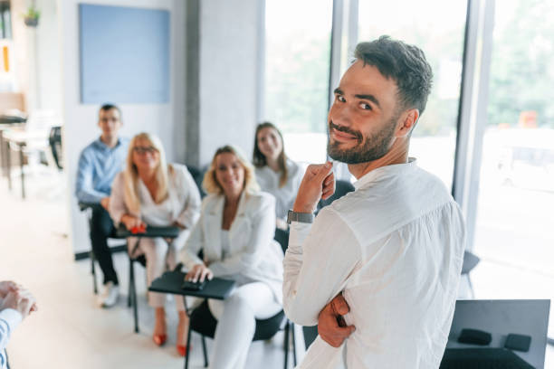 istock Man looking behind into the camera. Master class. Group of professional business people is in the office 1419062792