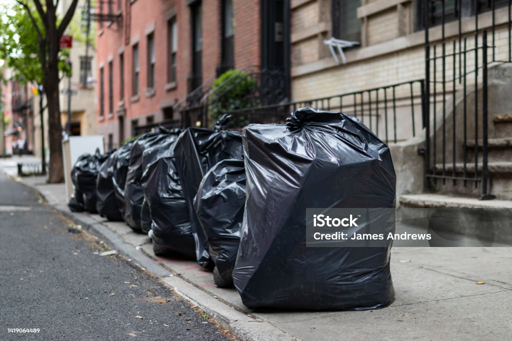 Black Garbage Bags along a Residential Street in Greenwich Village of New York City A row of black garbage bags along a residential street and sidewalk waiting to be picked up in Greenwich Village of New York City Garbage Stock Photo
