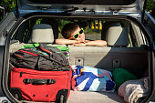 istock Adorable kid boy wearing sunglasses sitting in car trunk. Portrait of Happy child with open car boot while waiting for parent get ready for vocation. Family trip traveling by car concept 1419064569