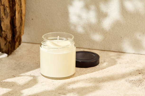 istock Simple composition with aromatic burning candle in jar. Mockup soy wax candle with wick in natural style. Scented handmade candle with tree bark.  Handmade spa product  from soy wax in glass. 1419065872