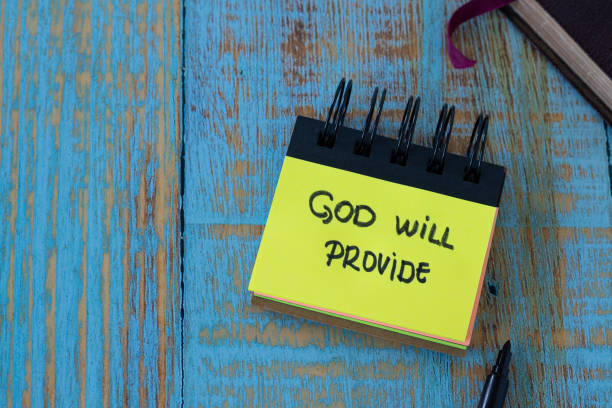 istock God will provide, a handwritten text note in a small notebook with a closed Holy Bible Book on a rustic wooden background 1419067182