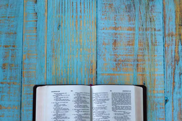Open Holy Bible Book on a blue rustic wooden background with copy space. Top table view. Studying and reading Christian Scriptures, biblical concept.