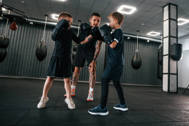 istock Having fun by practicing. Young tattooed coach teaching the kids boxing techniques 1419070276