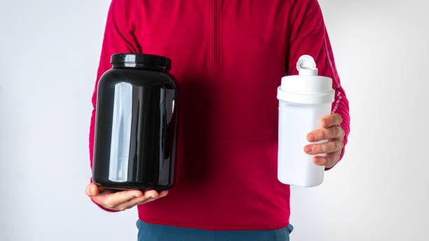 istock Athletic man with a protein can and shaker on a white background 1419071678