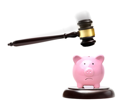 Sad piggy bank under the law gavel - isolated on a white background