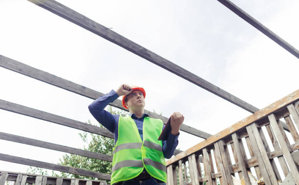istock Building inspector. Man in a hard hat and a yellow reflective vest examines damaged structures and inspects the building. Damage assessment. Preparing for the repair or construction of a building 1419072633