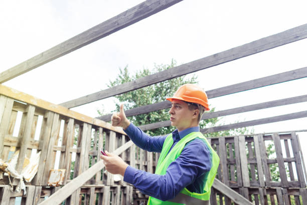 istock Building inspector. Man in a hard hat and a yellow reflective vest examines damaged structures and inspects the building. Damage assessment. Preparing for the repair or construction of a building 1419072683