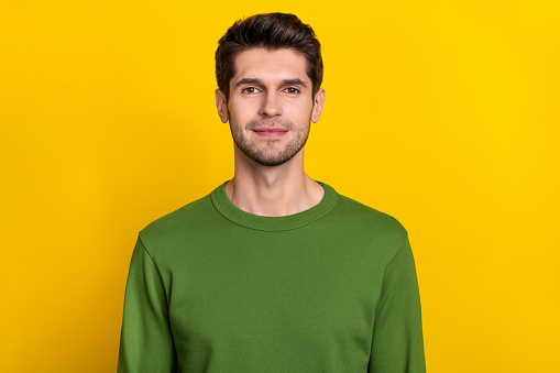 Photo of pretty attractive young guy dressed green pullover smiling isolated yellow color background.