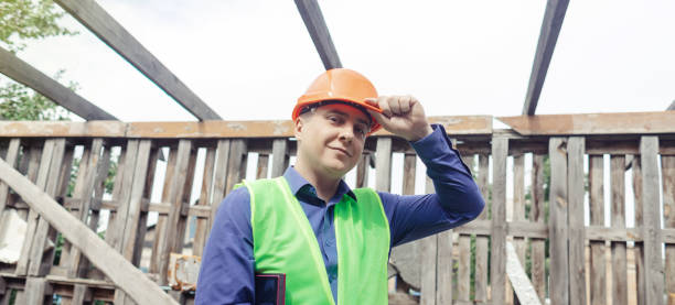 istock Building inspector. Man in a hard hat and a yellow reflective vest examines damaged structures and inspects the building. Damage assessment. Preparing for the repair or construction of a building 1419074194