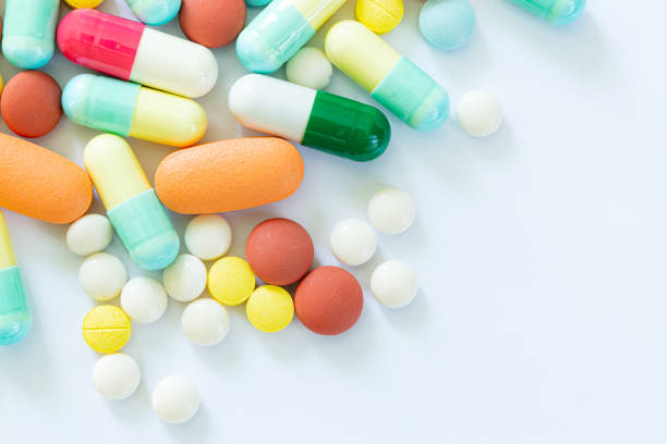 píldoras y cápsulas sobre un fondo blanco, diferentes píldoras de colores sobre fondo blanco - capsule pill medicine antibiotic fotografías e imágenes de stock