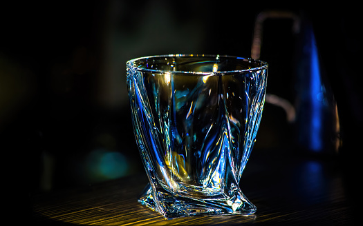 An empty glass beaker glows on a dark background