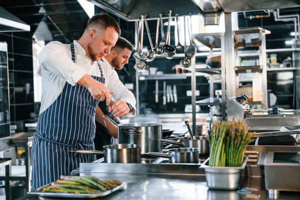istock Boiling and adding ingredients. Kitchen workers is together preparing the food 1419075618