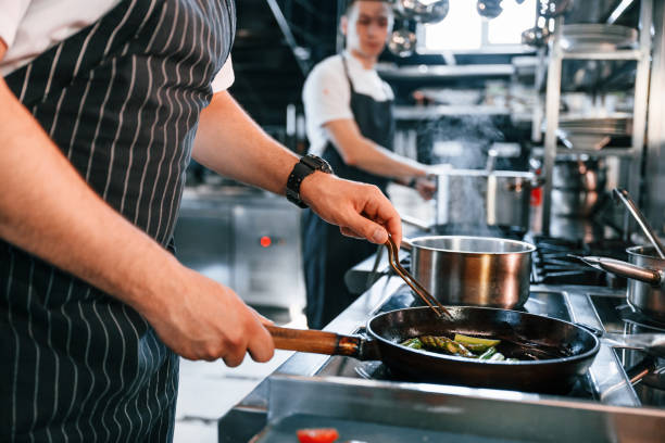 istock Side view. Kitchen workers is together preparing the food 1419075700
