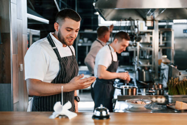 istock Standing near the table with bell. Kitchen workers is together preparing the food 1419076597