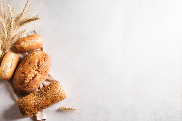 Fresh Bread Assortment of various delicious freshly baked bread on white background, copy space. Variety of artisan bread composition and ears of wheat. bread stock pictures, royalty-free photos & images