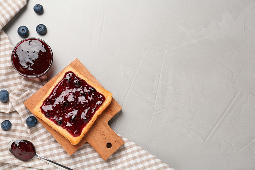 Toast with blueberry jam served on grey table, flat lay. Space for text