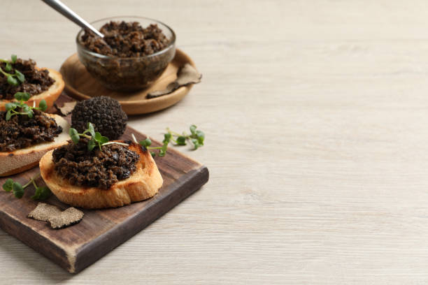 Delicious bruschettas with truffle sauce and microgreens on white wooden table. Space for text