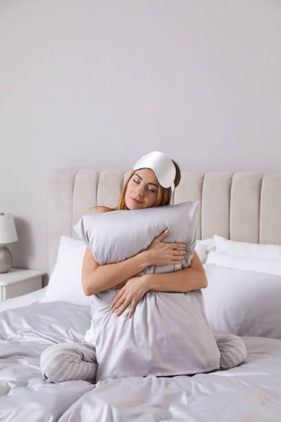 istock Beautiful woman hugging pillow on comfortable bed with silky linens 1419089162