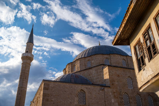 Bewölkter, sonniger Himmel der Stadt Antalya. Zerbrochene Fenster des alten historischen Hauses neben der historischen Moschee.Built in the 18th century in the Kalekapisi district, the mosque is one of the most important Ottoman mosques in the city. Tekeli Mehmet Pasha Mosque.