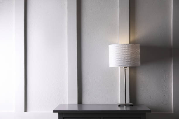 istock Wooden table with lamp near white wall in room, space for text 1419090784