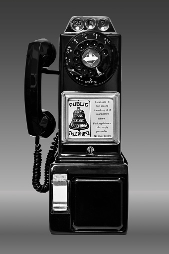 Black and White photo of a classic Western Electric rotary-dial payphone commonly used throughout the United Staes of America prior to the adoption of the push-button dial phone.