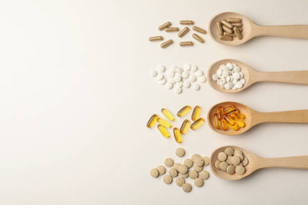 istock Wooden spoons and different dietary supplements on white background, flat lay. Space for text 1419092106