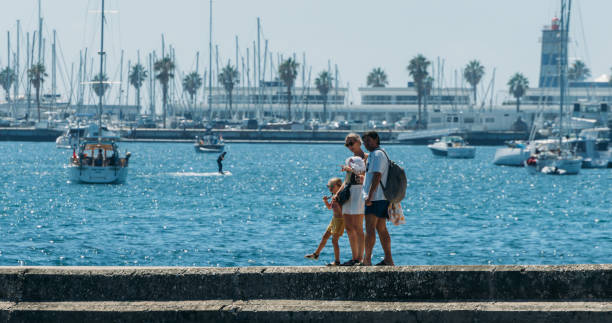 Family walk on pier in Cascais, Portugal with bay and boats on the background stock photo
