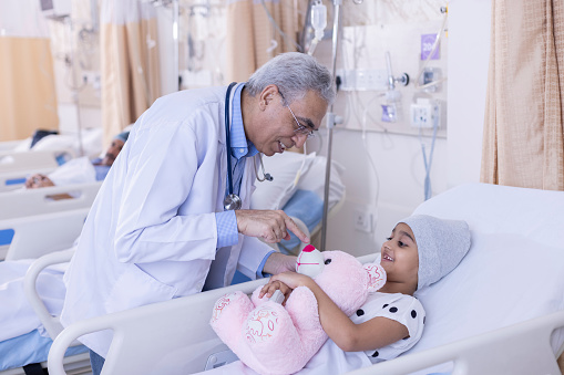 Doctor examining and having fun with little girl patient at hospital.