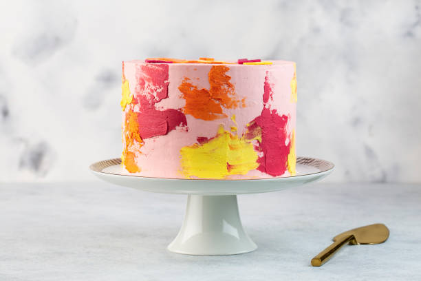 istock Rainbow cake with whipped cream top on the white background. Birthday cake with multicolored cream cheese frosting. 1419093597