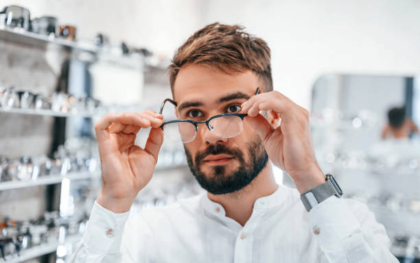 istock Stylish man with beard choosing glasses in the optics store 1419095338