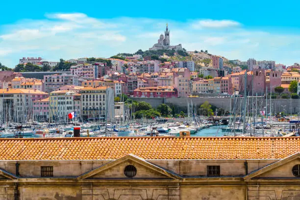 The Vieux Port of Marseille. Boats moored in the harbor. Cathedral Notre Dame de la Garde high on a hill overlooking the city in the background. Cote d Azur, South of France, Europe. Colorful travel image.