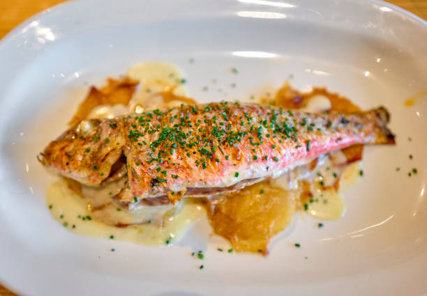 istock Grilled Red Mullet serverd over baked potatoes and dressing with chives. 1419100390