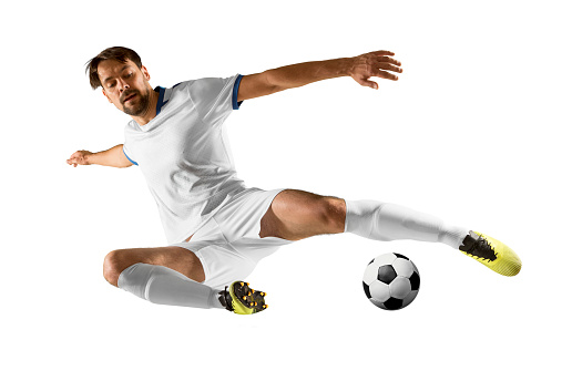 Full length of aged 18-19 years old with black hair generation z male soccer player running in front of white background who is in concentration and holding soccer ball and playing soccer - sport and using sports ball