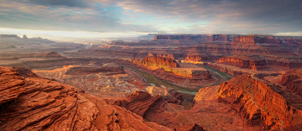 Deadhorse Point Sunrise Panoramic, Sunrise from the look out view over Dead Horse Point State Park, a state park of Utah in the United States, featuring a dramatic overlook of the Colorado River and Canyonlands National Park, so named because of its use as a natural corral by cowboys in the 19th century, where horses often died of exposure canyonlands national park stock pictures, royalty-free photos & images