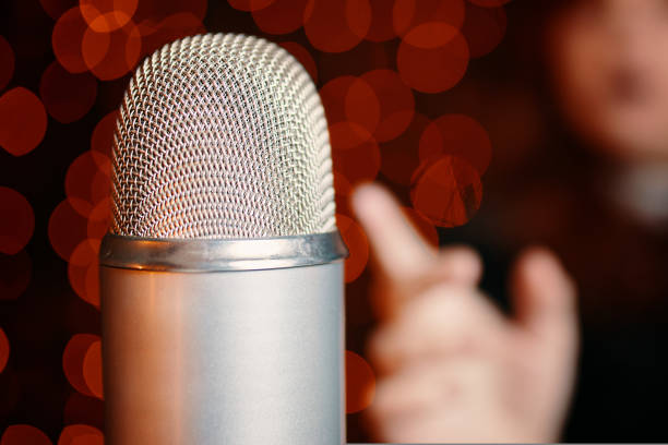 istock Woman pulls hand to microphone for sing at concert. 1419101218
