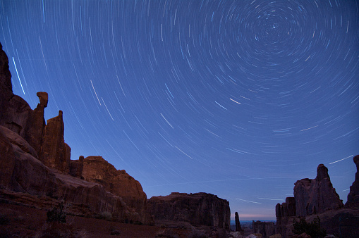 Summer nights in Arches national park, with the Milky Way rising to be perpendicular with Delicate Arch (lit by a separate photo tour). The b/g glow is Moab, 8 miles away.