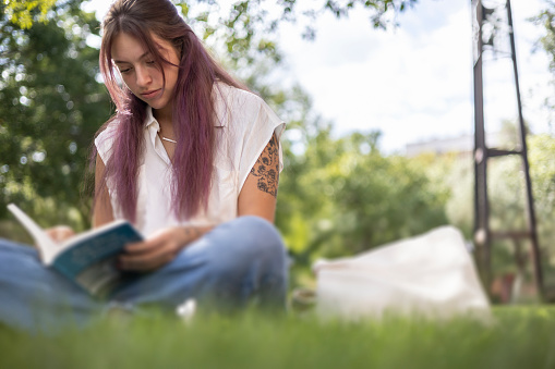 A student in her 20's studying on the the campus outside
