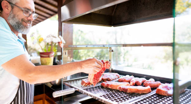 istock Smiling man putting steaks on a barbecue grill outdoors 1419111475
