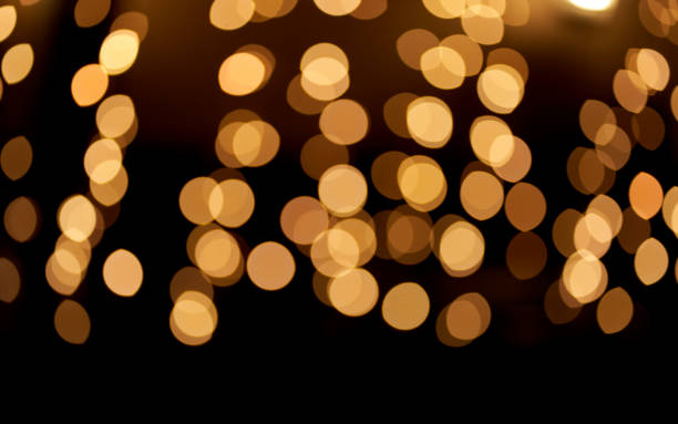 istock Abstract glowing bokeh lights highlighted on a black background. Festive golden glowing background with yellow lights. Overlay bokeh for your design. 1419113029