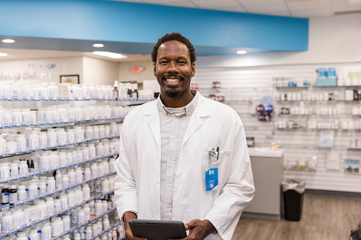 The mid adult pharmacist poses for a photo in his successful store.