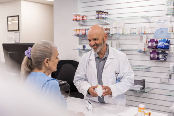 istock Mature male pharmacy tech smiles while listening to senior customer 1419113364
